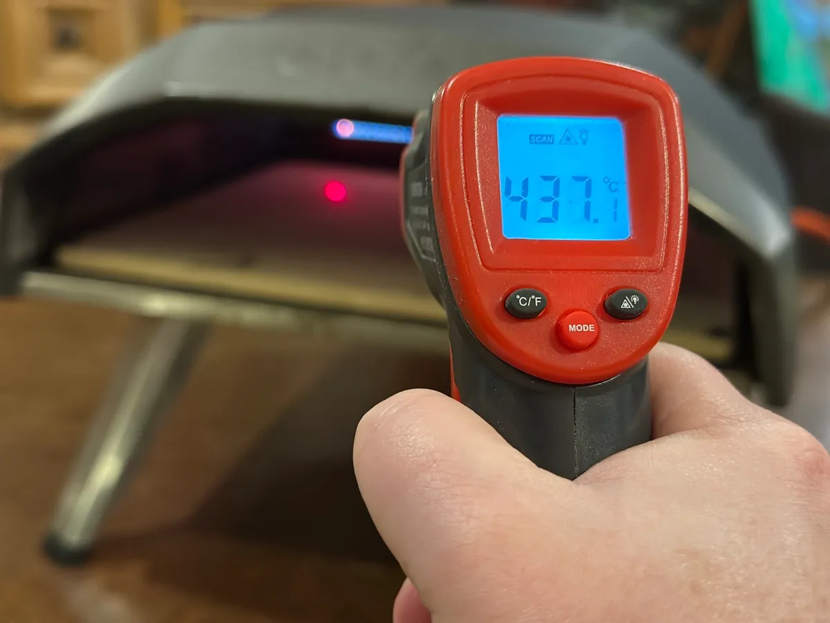 Thermomètre infrarouge pointé vers la pierre de cuisson de l'Ooni Koda 12, affichant 430°C — la température minimale avant d'enfourner