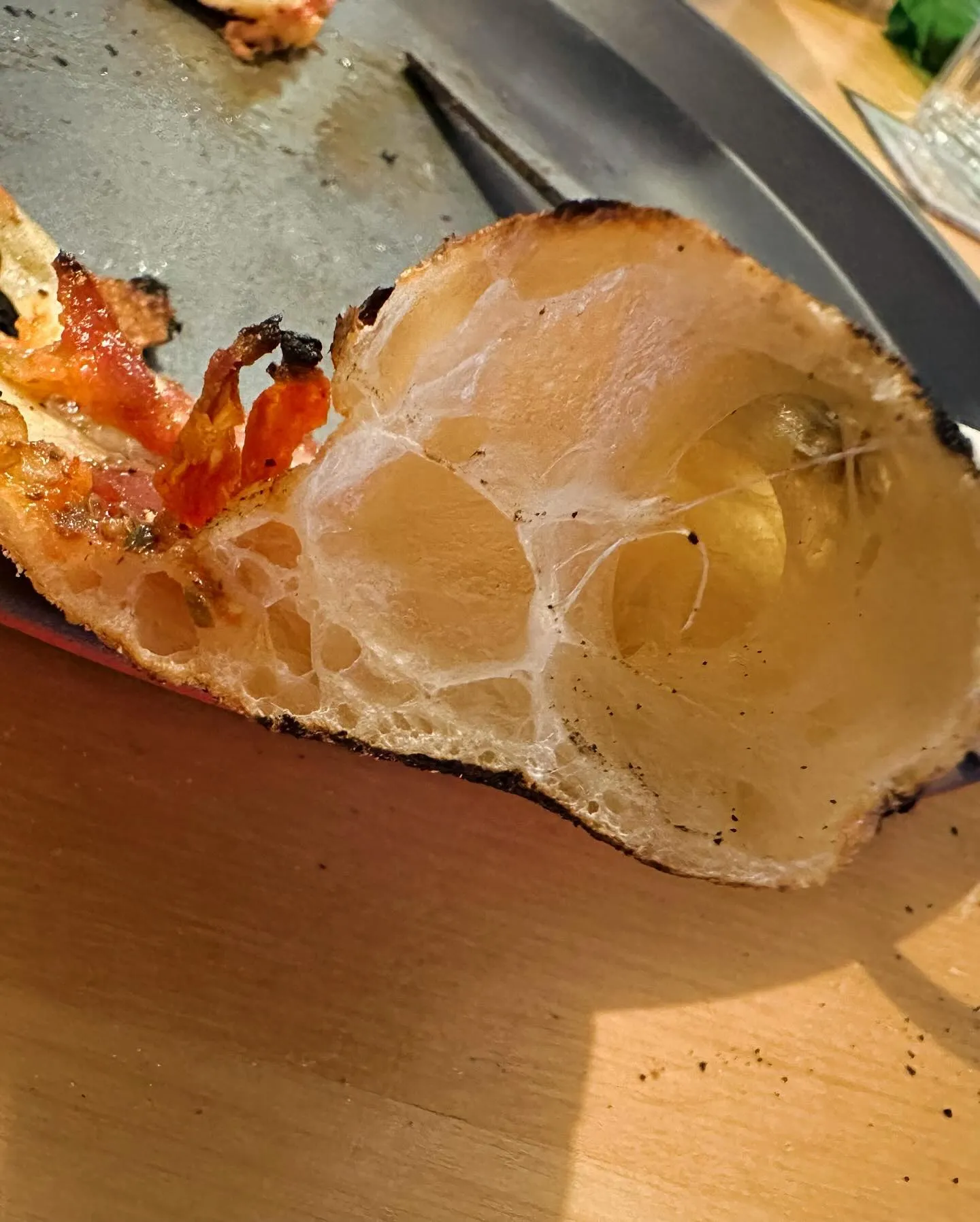 Pizza napolitaine fraîchement cuite dans un Ooni Koda 12 : cornicione léopardé avec taches caramelées et alvéoles bien visibles à travers la croûte